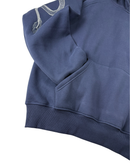 Close-up of a navy blue sweatshirt showing the sleeve with white dragon embroidery, a ribbed cuff, and a front pocket against a white background.