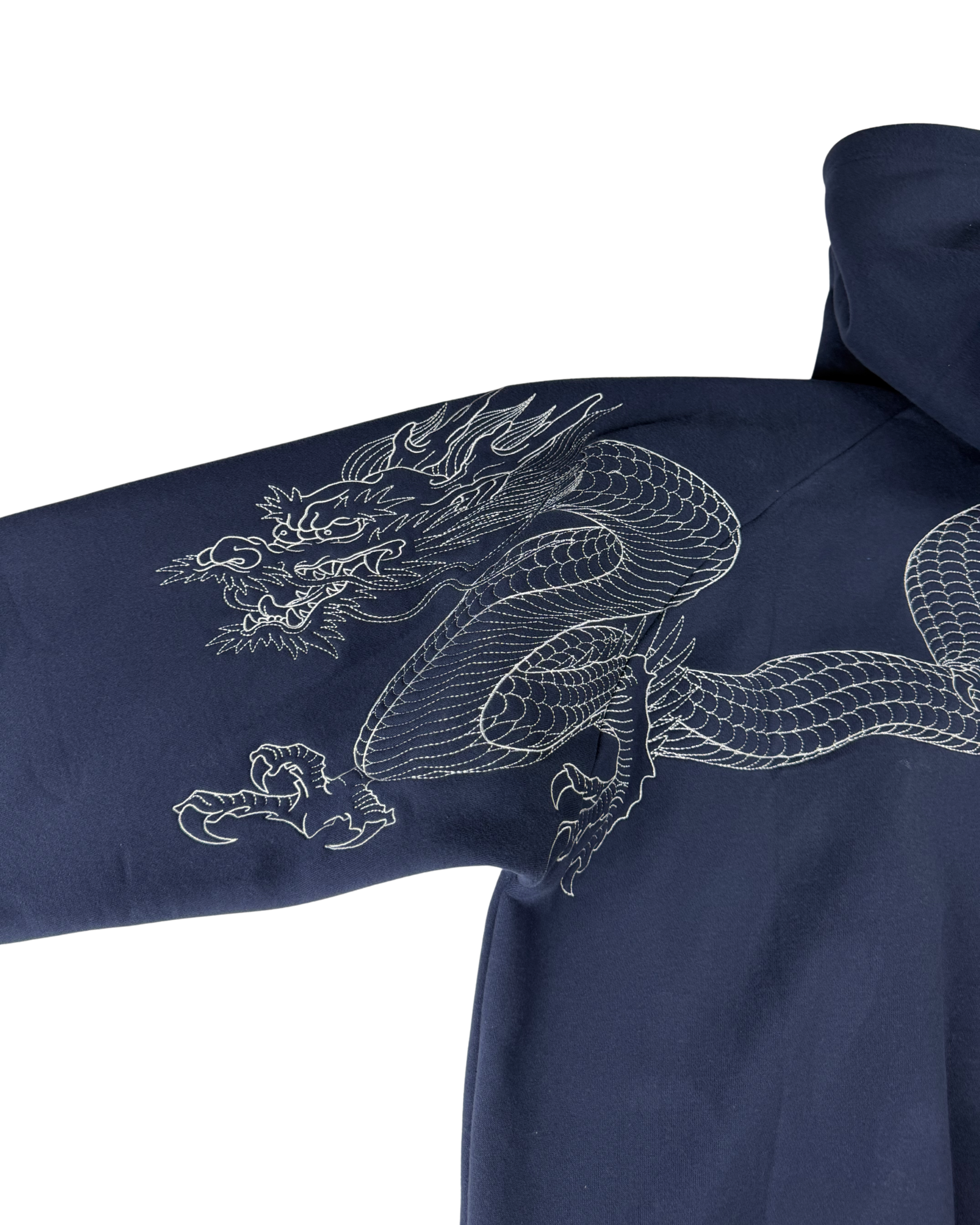 Close-up of a navy blue hooded garment with a large white embroidered dragon design across the sleeve and upper chest, shown against a plain white background.