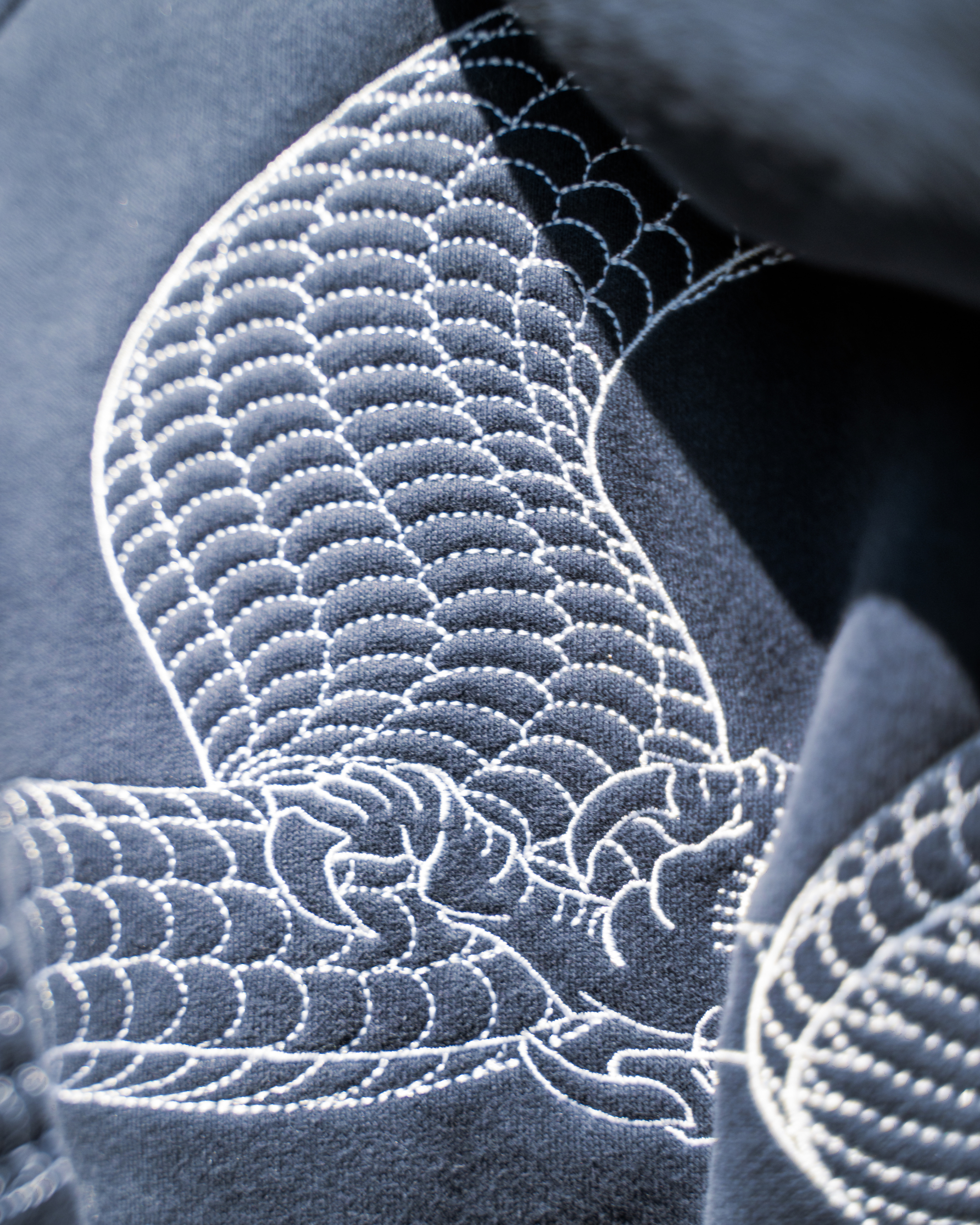 Close-up of a dark navy fabric with intricate white Japanese-style embroidery.